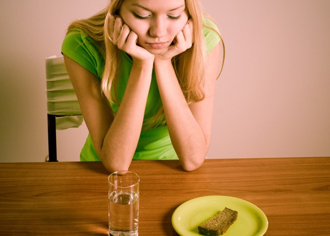 Ein Mädchen sitzt vor einem Glas Wasser und Brot