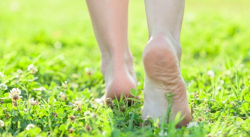 die Frau geht ohne Schuhe auf dem Rasen